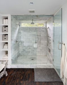 a walk in shower sitting inside of a bathroom next to a wooden floor and white walls