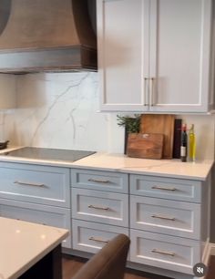 a kitchen with white cabinets and marble counter tops