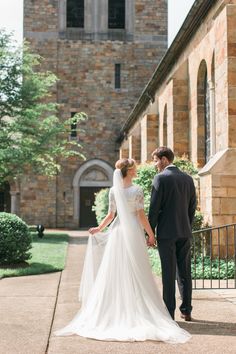 a bride and groom standing in front of an old church