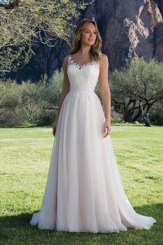 a woman in a wedding dress standing on the grass