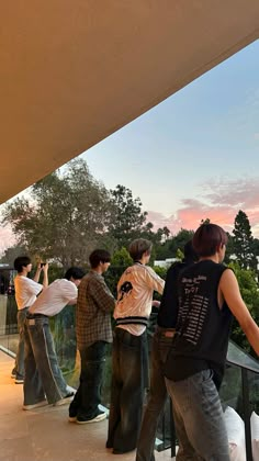 several people standing on a balcony looking at the sky and trees in the back ground