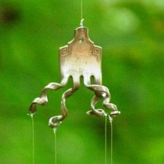 a metal wind chime hanging from a wire with green grass in the back ground