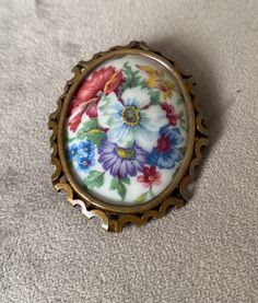 a brooch with flowers on it sitting on top of a white cloth covered floor