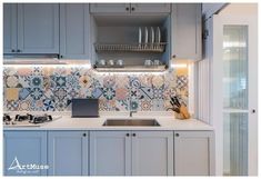 a kitchen with blue cabinets and tile backsplash, white countertops and gray cupboards