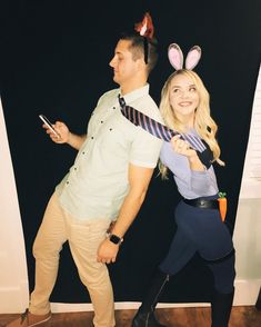 a man and woman dressed up as bunny ears, one holding a cell phone while the other holds a tie