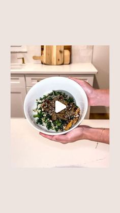 a person holding a bowl of food in their hand with a video playing on it