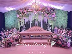 a pink couch sitting under a white canopy covered in flowers and greenery next to a chandelier