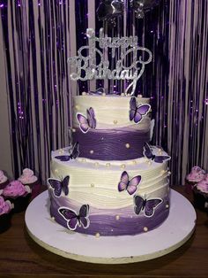 a three tiered cake with purple butterflies on it