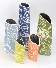 four different colored vases with designs on them sitting side by side in front of each other