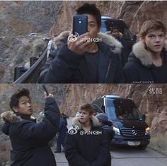 two people are taking pictures with their cell phones in front of a mountain side cliff