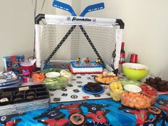 a table topped with lots of food next to a goalie net on top of a blue blanket