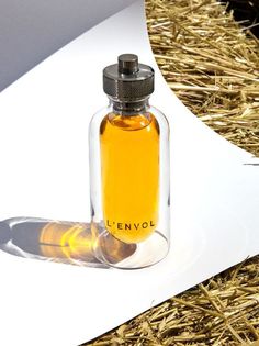 an empty glass bottle sitting on top of hay next to a white piece of paper