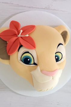 a close up of a cake on a plate with a lion face and flower in it