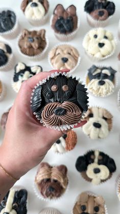 a person holding up a cupcake in front of a bunch of dogs on it