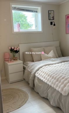 a bed room with a neatly made bed next to a window and a rug on the floor