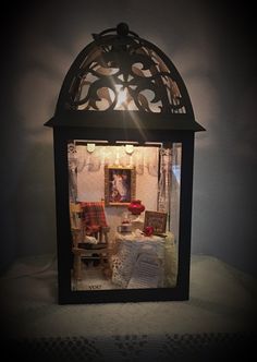 a lighted lantern is sitting on a table with some pictures in it's glass case