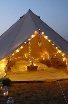 a white tent with lights on it in the sand