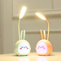 two cute little lamps sitting on top of a table next to each other with eyes