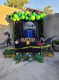 the entrance to an event decorated with balloons and decorations for a dinosaur themed birthday party