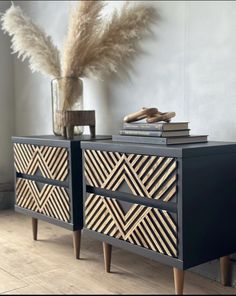 a black and gold dresser with some books on top of it next to a plant