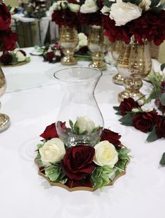 there is a vase with roses in it and other flowers on the table behind it