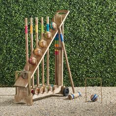 a wooden toy set with baseballs, bats and balls in front of a hedge