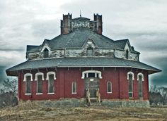 an old red house sitting on top of a hill