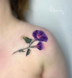 a woman's shoulder with a purple flower tattoo on the left side of her chest