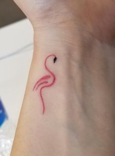 a small tattoo on the wrist of a woman's left arm with a pink flamingo