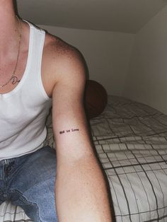 a man sitting on top of a bed with a tattoo on his arm and chest