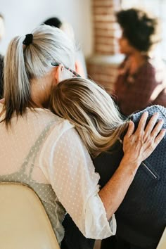 two women hugging each other while sitting in chairs