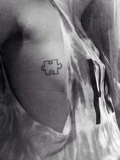 a woman with a tattoo on her chest that has a puzzle piece in the middle