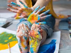 the child is sitting on the floor with his hands painted in different colors and shapes