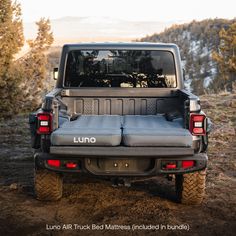 the back end of a black jeep parked on top of a dirt field