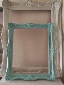 a white and blue frame sitting on top of a bed next to a wall mounted mirror