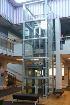 the inside of an office building with glass walls and stairs leading up to two floors