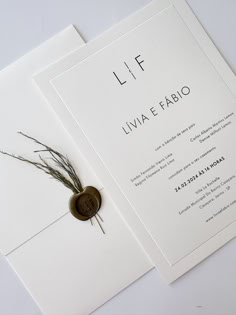 a wedding card with a button on it and some grass in the middle, sitting next to each other