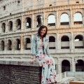 a woman sitting on top of a brick wall next to an old roman collise