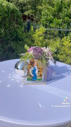 a table that has some flowers on it and a picture in the center with a woman's face