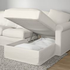 a white couch with an open pull out bed underneath it on a carpeted floor