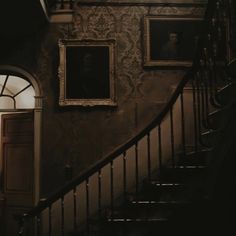 a staircase with pictures on the wall and an open door