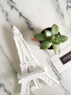 a small plant sits next to the eiffel tower on a marble countertop