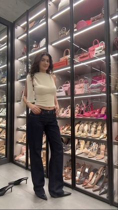 a woman standing in front of a display case filled with shoes and handbags,