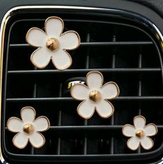 three white and gold flower shaped knobs on the front of a black grill door