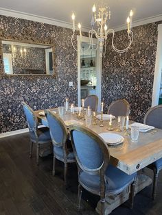 a dining room table with blue chairs and a chandelier hanging from the ceiling