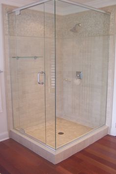 a bathroom with a glass shower door and wooden floor