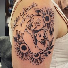 a woman with a tattoo on her arm holding a baby bear and sunflowers