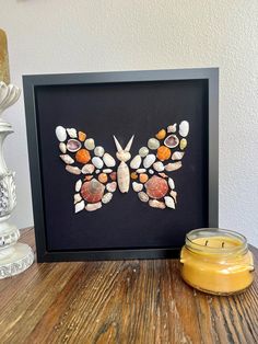 a butterfly made out of seashells on a table next to a jar of honey