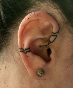 a woman with a black and white tattoo behind her ear