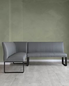 a gray couch sitting on top of a wooden floor next to a white wall with a black metal frame